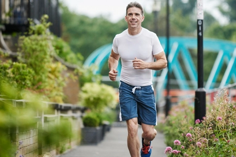 A man running along an urban path surrounded by plants