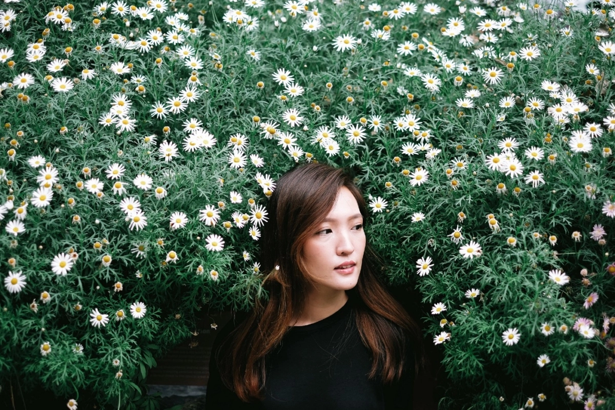 Woman sitting in front of a large flowery bush