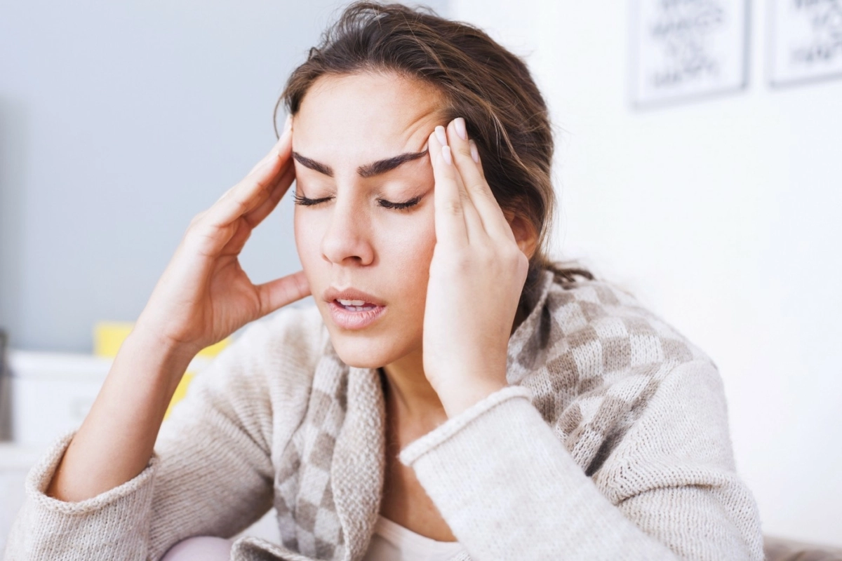 Woman with her hands on her temples and a pained look on her face