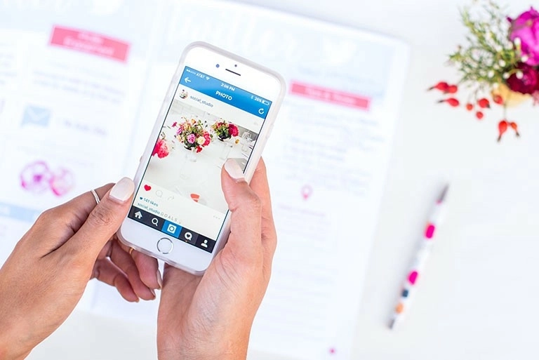 A person's hands holding their smartphone, looking at social media