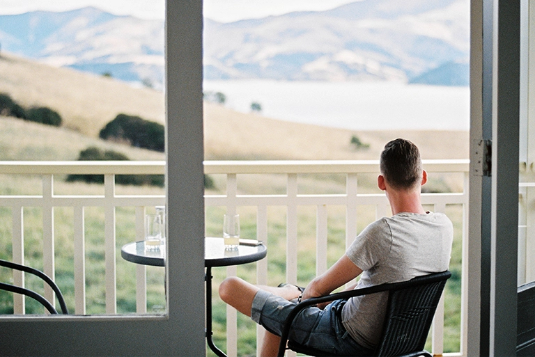 A man sitting on a balcony looking at mountains in the distance