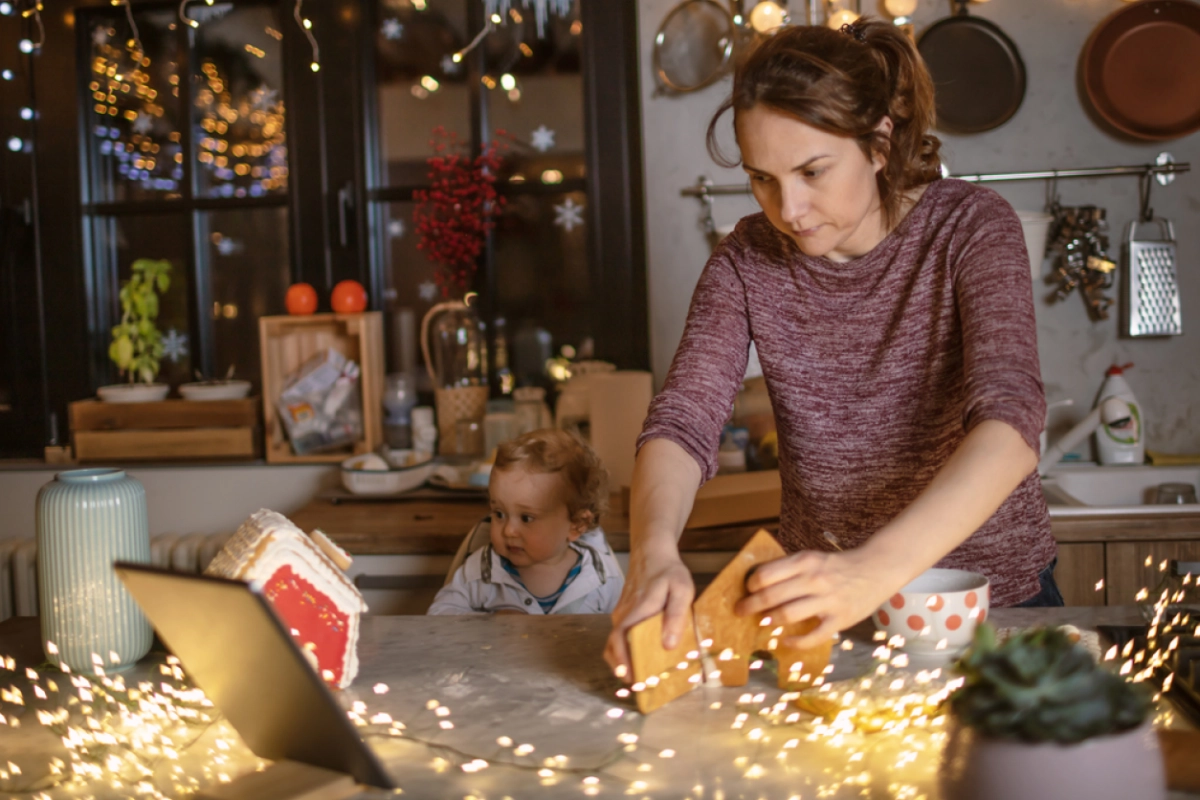 A woman works on a gingerbread house as she prepares for the holidays