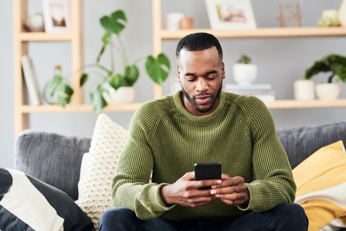 man sitting on couch using his phone for therapy session