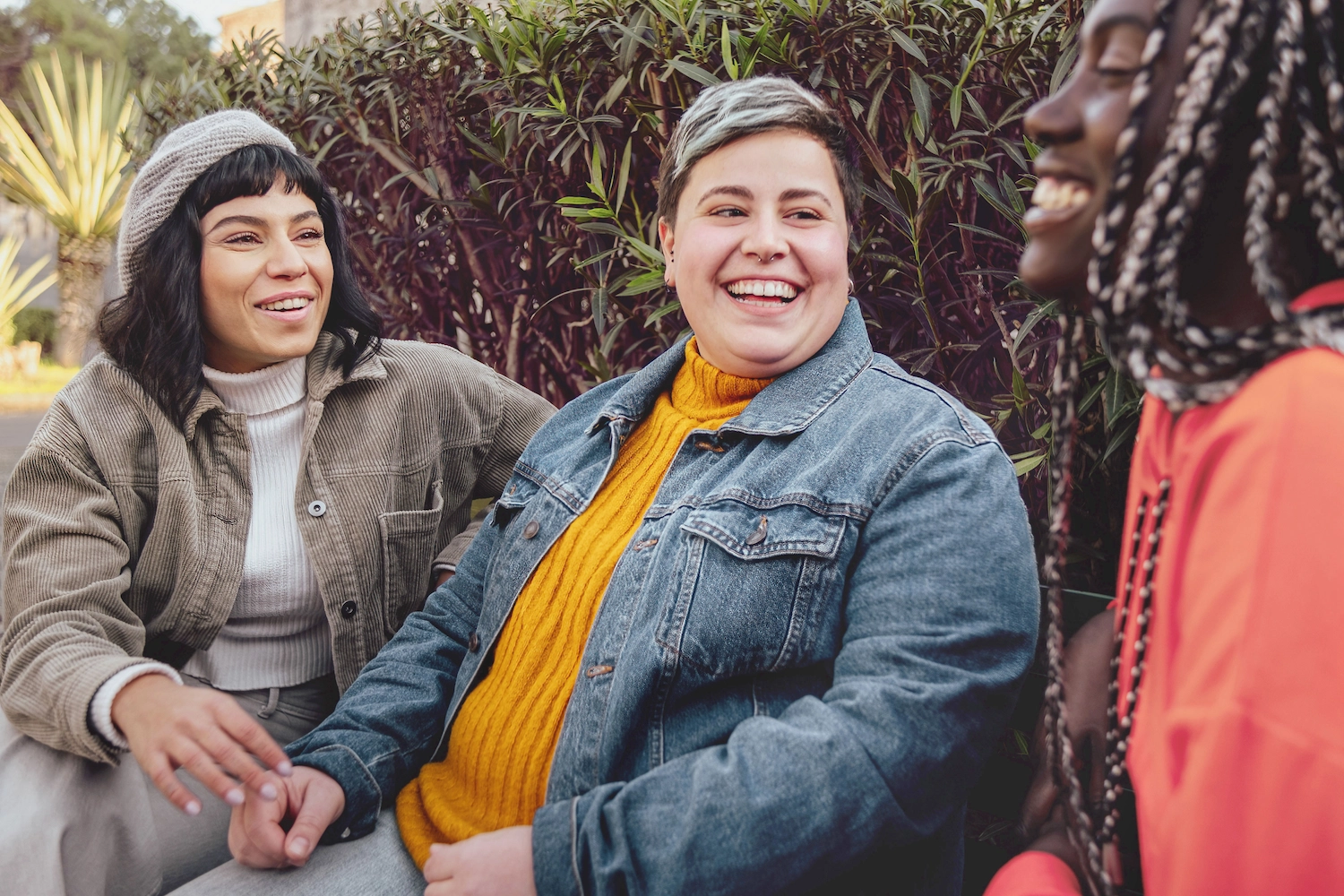 3 lgbtq+ people laughing on bench