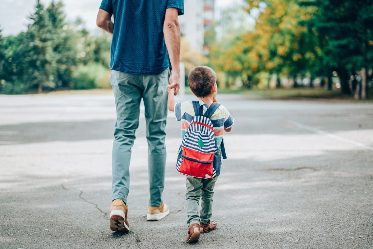 Dad and son holding hands walking to school