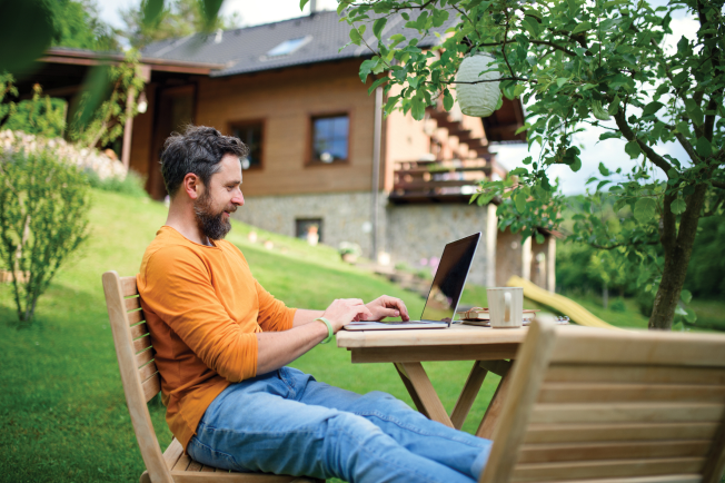 Man working in backyard on laptop
