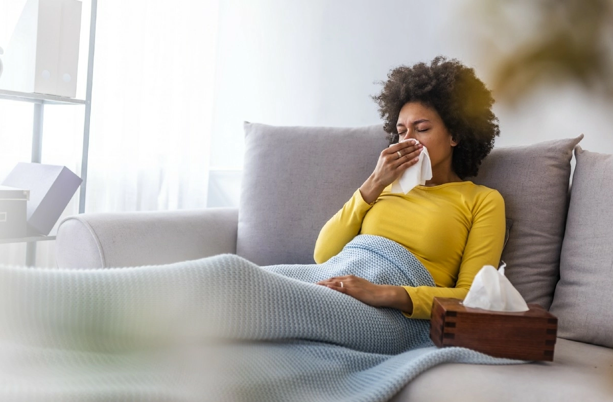 woman on couch blowing her nose