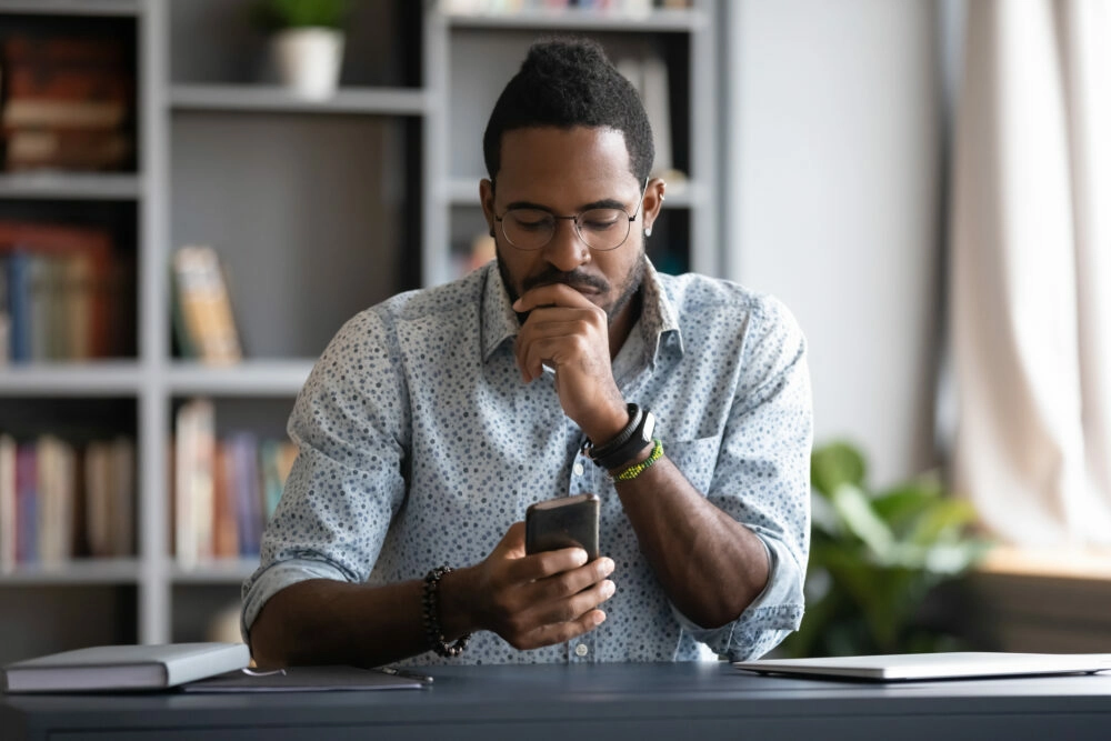 man sitting at desk checking phone