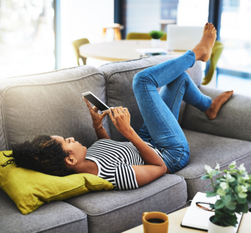 Woman lying on sofa with smartphone
