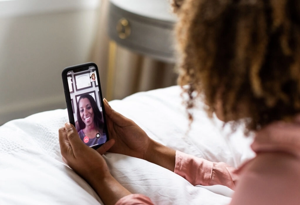 woman on bed using Doctor On Demand telehealth app