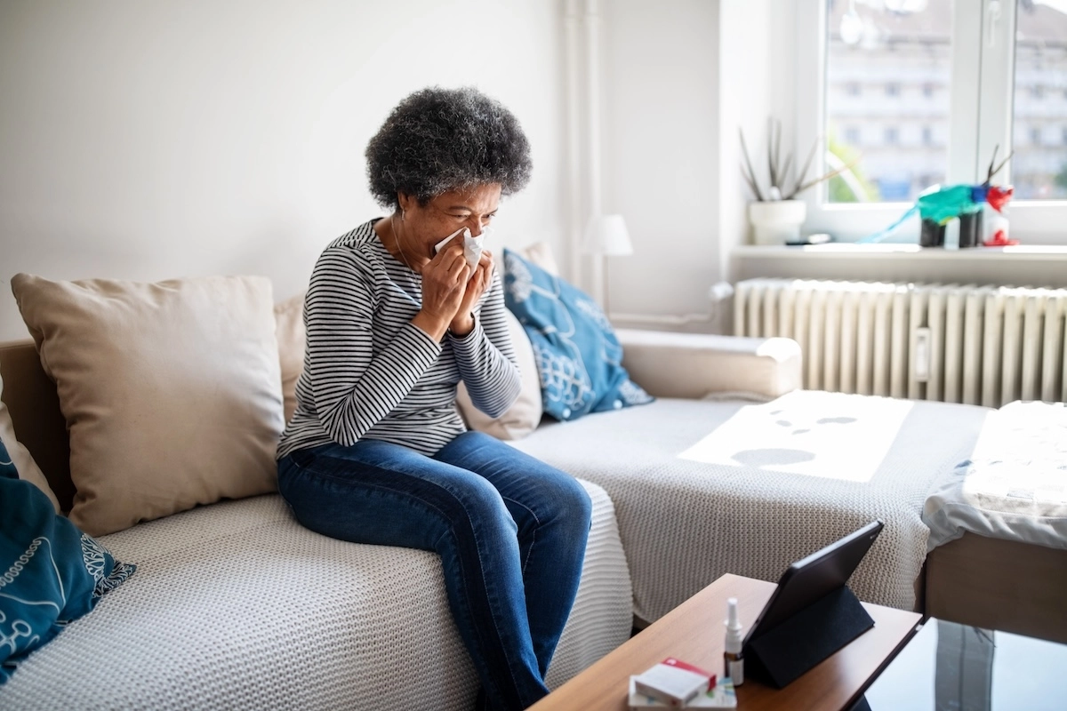woman blowing nose on couch