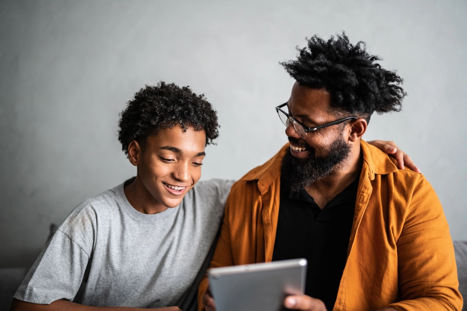 Father and son smiling looking at computer together.