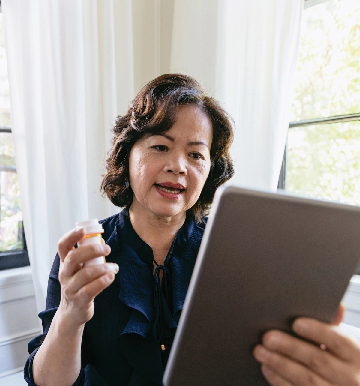 woman holding tablet and prescription bottle