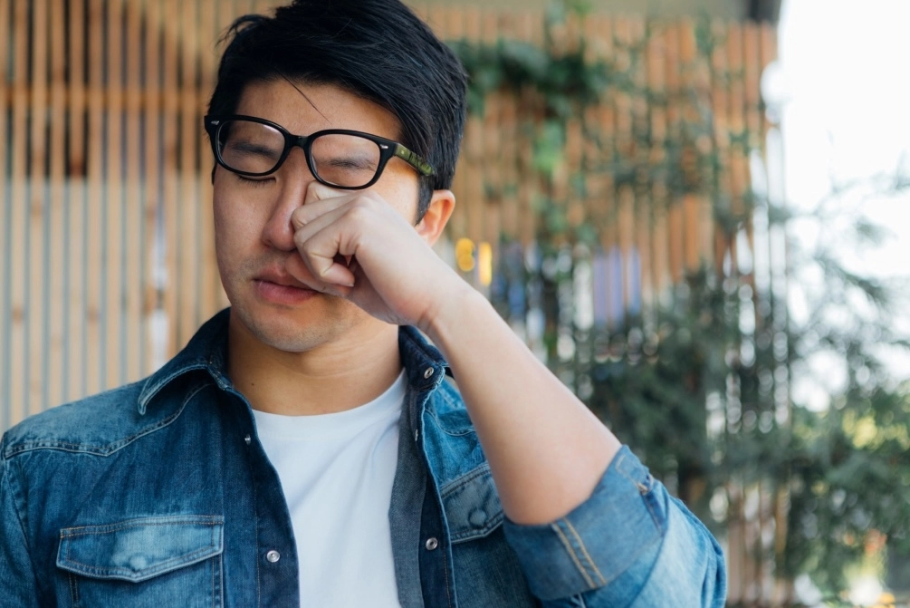 Young man rubbing his eye due to eye infection.