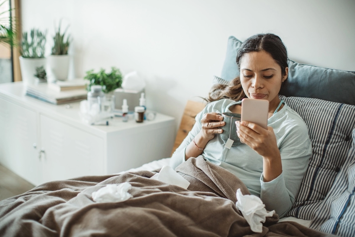 woman in bed with flu using virtual care to get online flu treatment