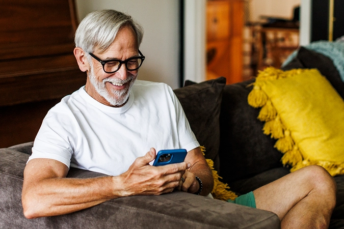 Older man sitting on the couch with his phone