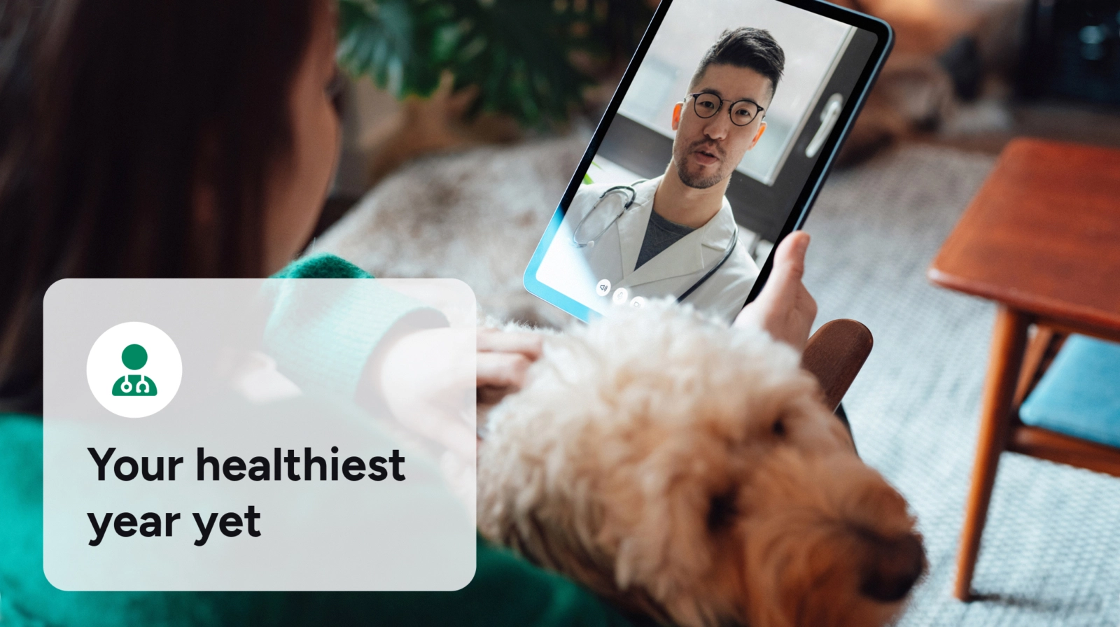 A person with a fluffy dog holds a tablet displaying a video call with a male doctor, and a graphic overlay reads "Your healthiest year yet".