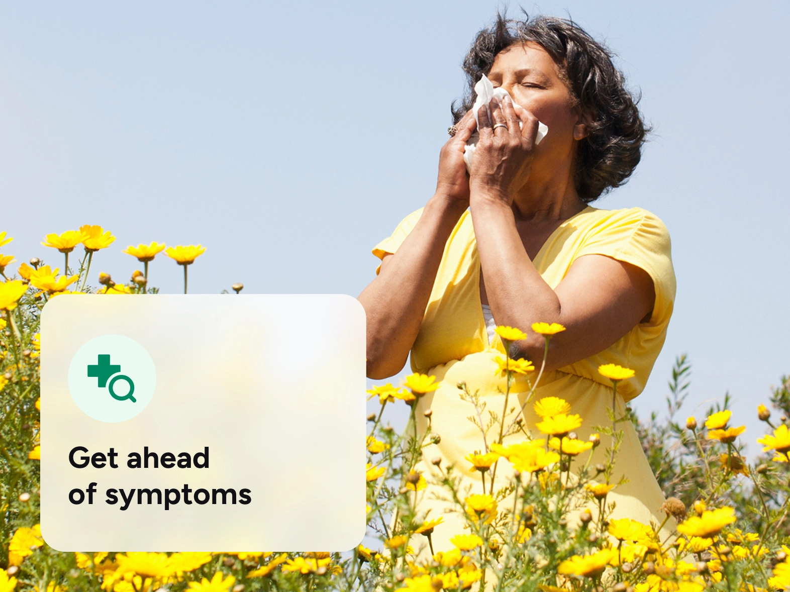 A woman sneezing outside while she is surrounded by yellow flowers