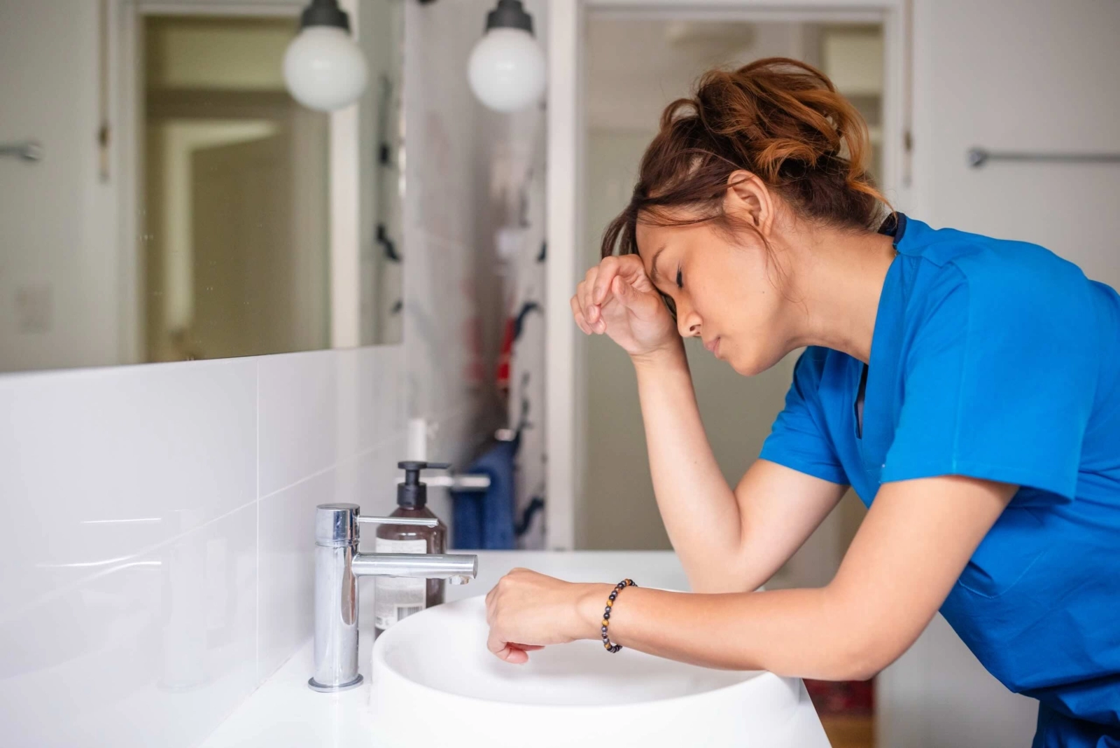 Woman leaning over sink feeling nauseous