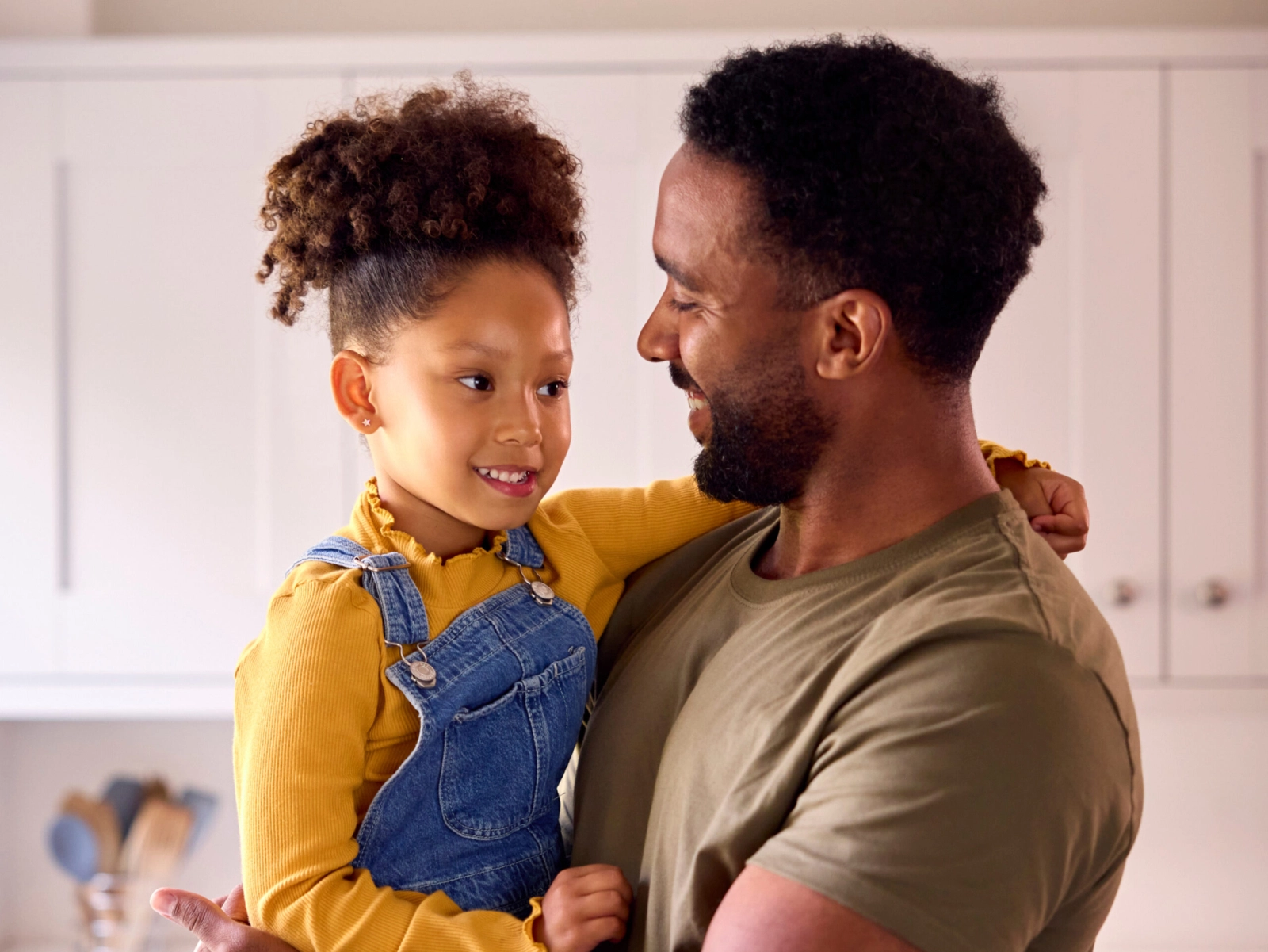 A father holding his daughter and smiling.